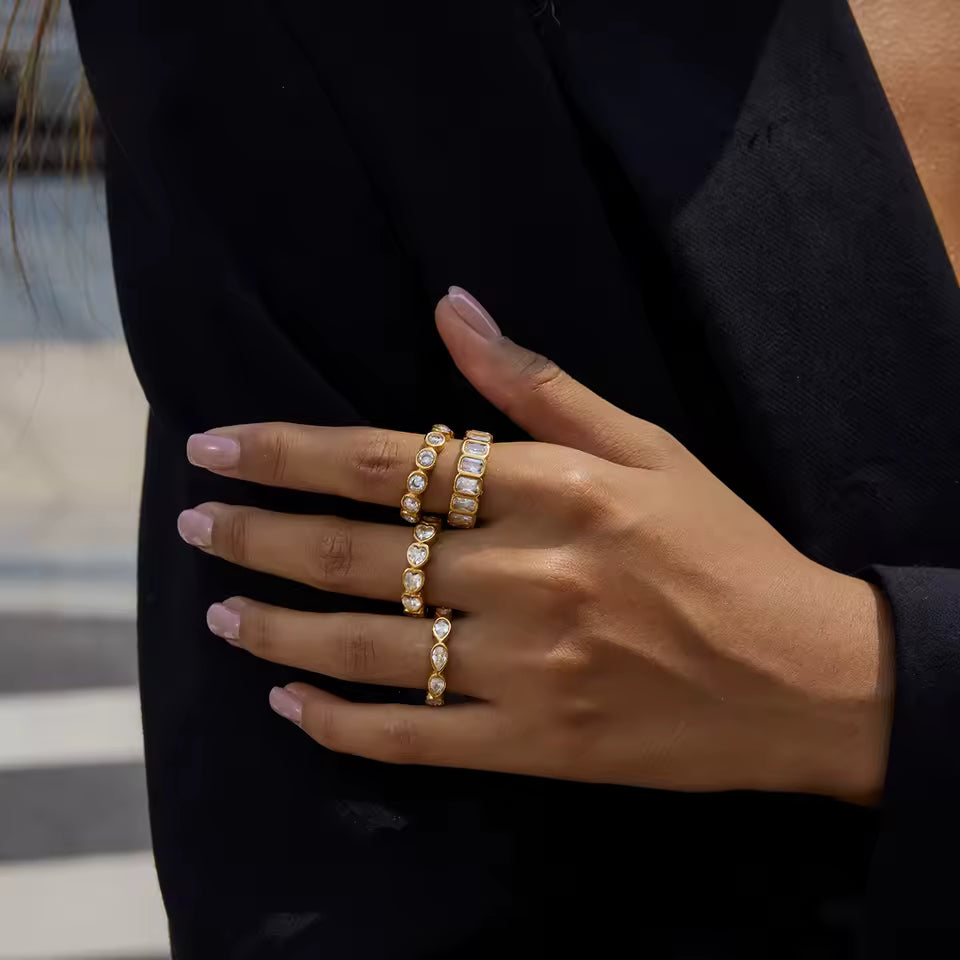 Hand wearing multiple gold rings with a blurred background