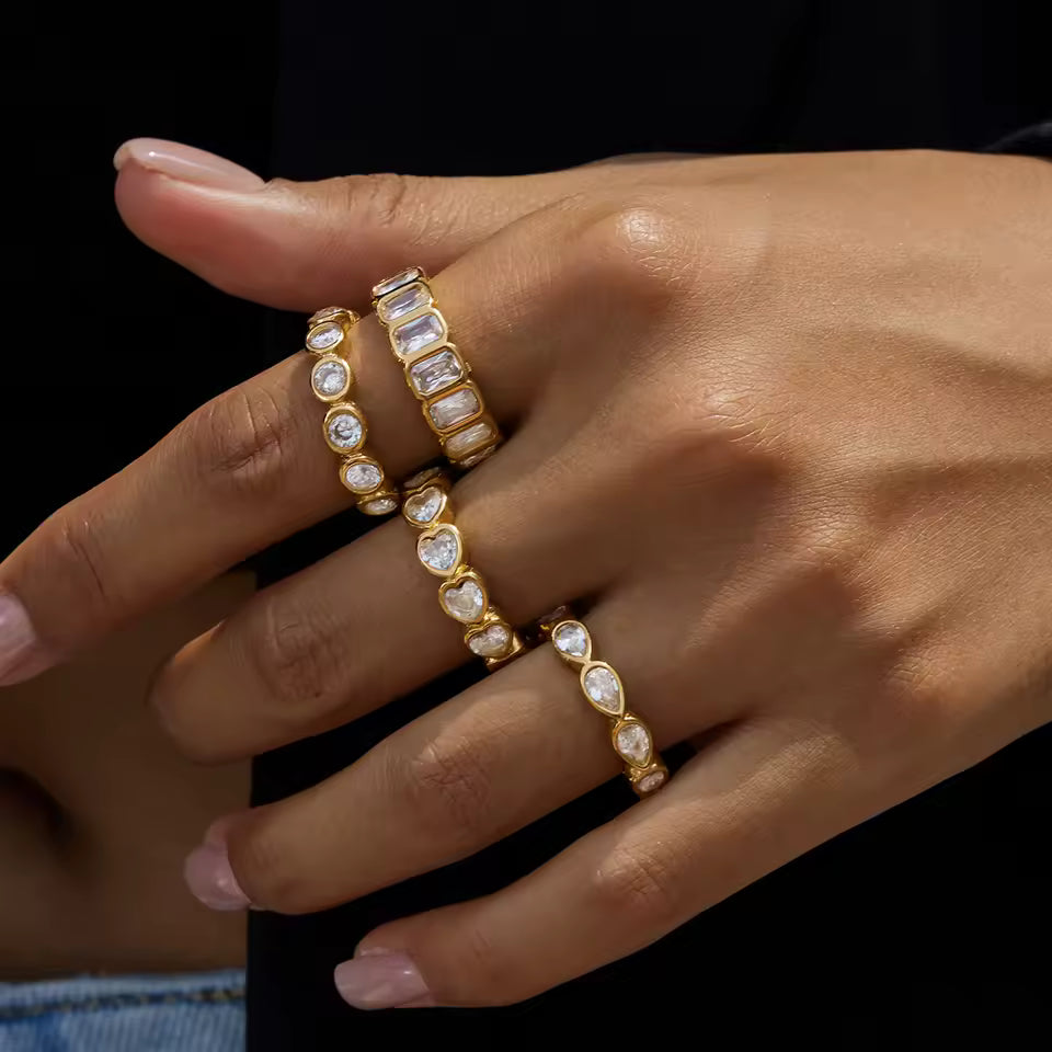 Close-up of a hand wearing gold rings with gemstones on a dark background