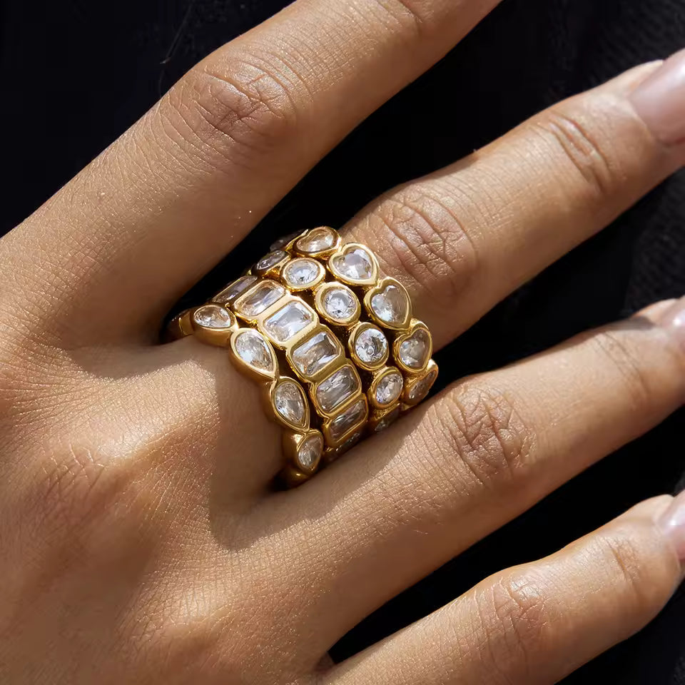 Gold ring with clear gemstones on a hand against a black background