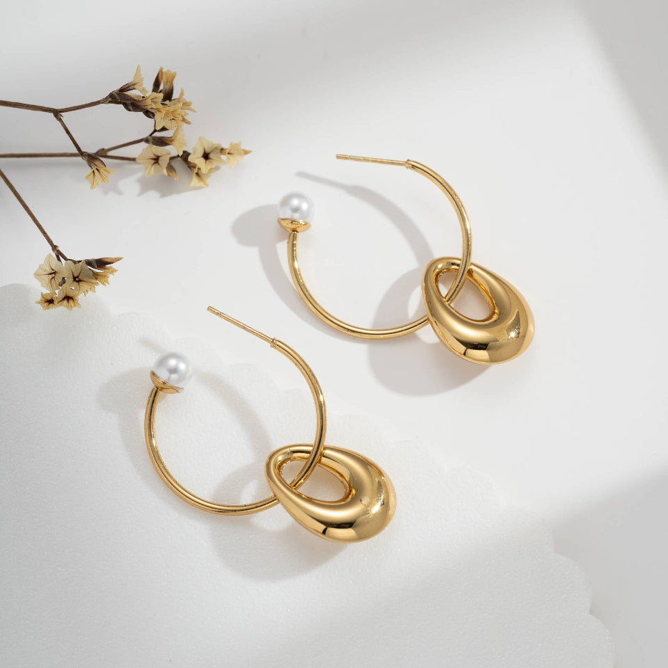 Gold hoop earrings with pearl accents on a light background