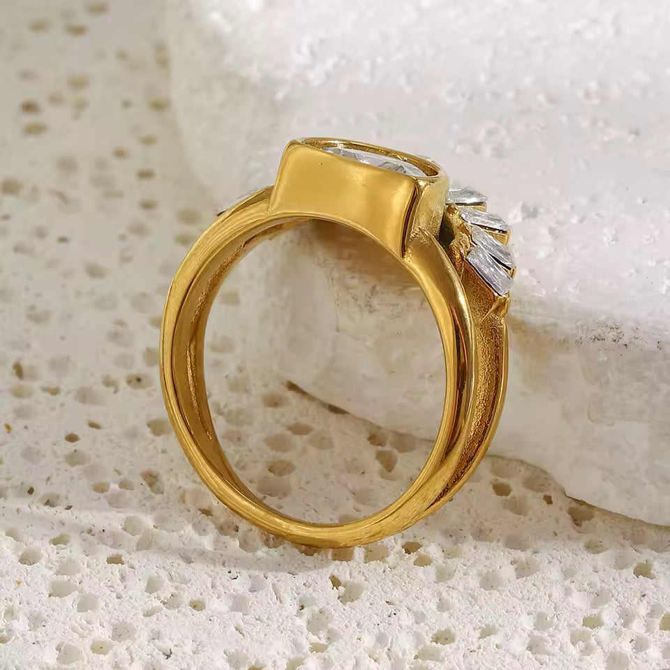 Gold ring with diamond accents on a textured white surface