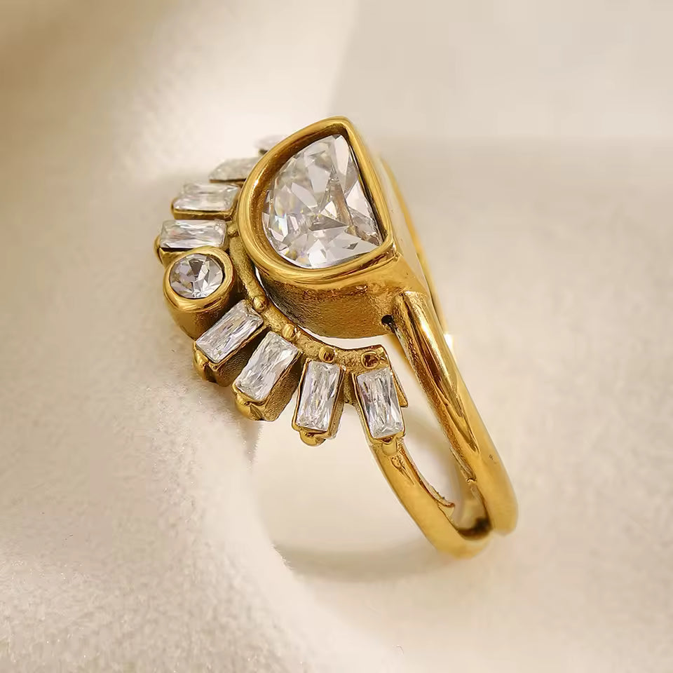 Gold ring with clear gemstones on a beige background