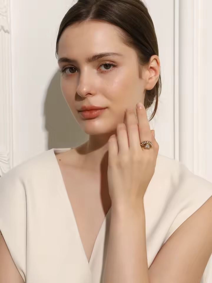 Woman wearing a gold ring on her finger against a neutral background