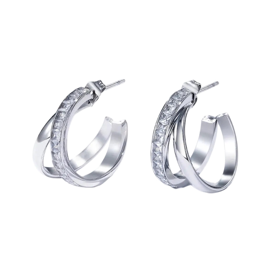 A pair of silver hoop earrings with a row of clear stones along one curve, displayed on a clean white background with soft shadows.