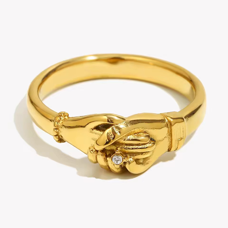 Gold ring with interlocking hands design on a white background