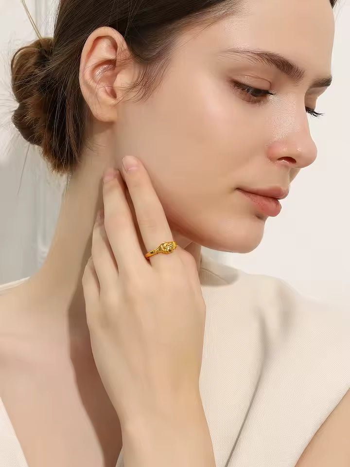 Woman wearing a gold ring on her finger, with a neutral background