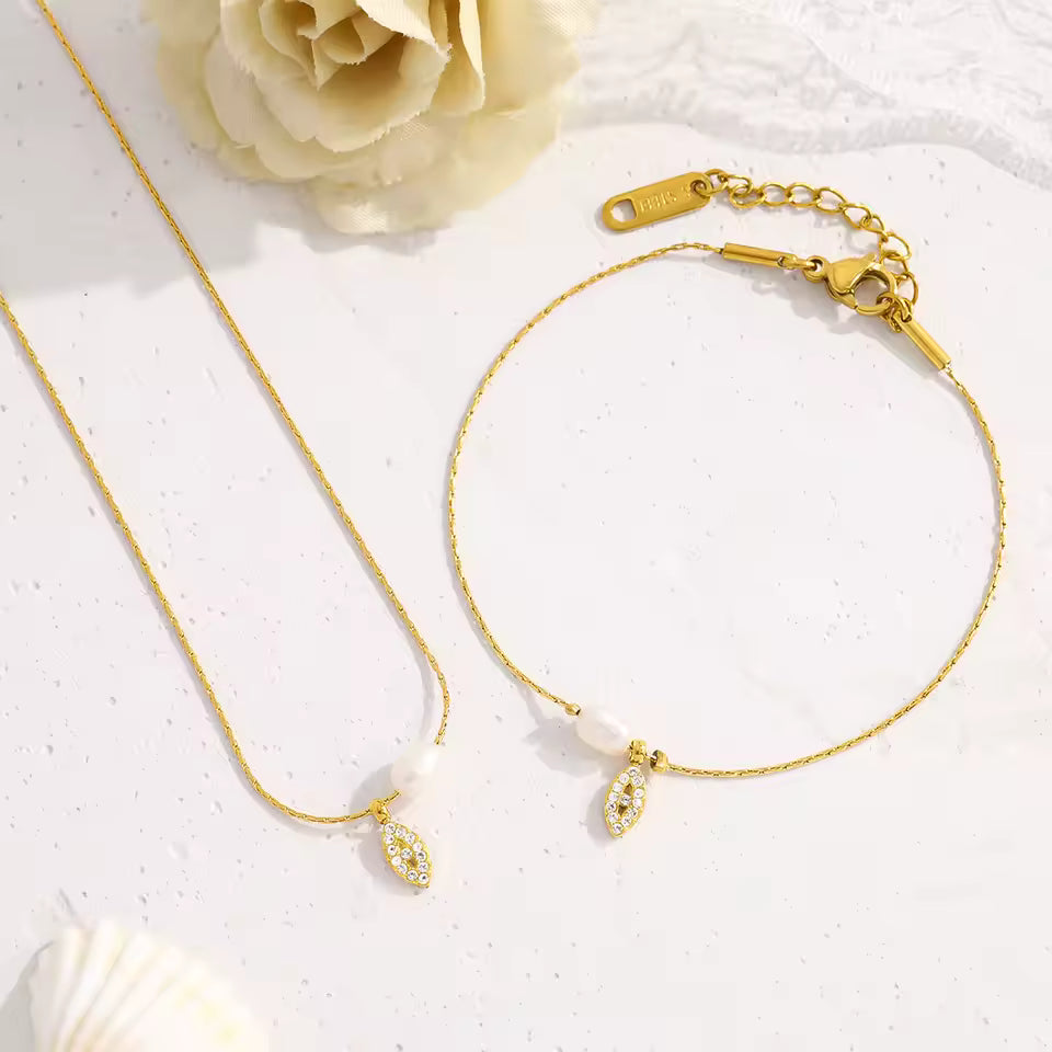 Gold necklace and bracelet set on a white background with a rose.
