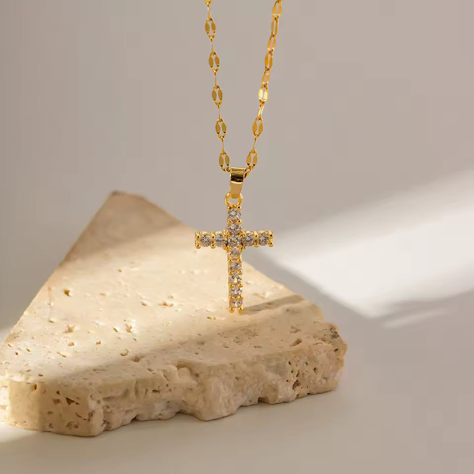 Gold cross necklace on a stone surface with a neutral background