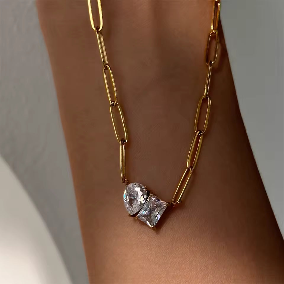 Paperclip gold chain with two large cubic zirconia's lying on arm