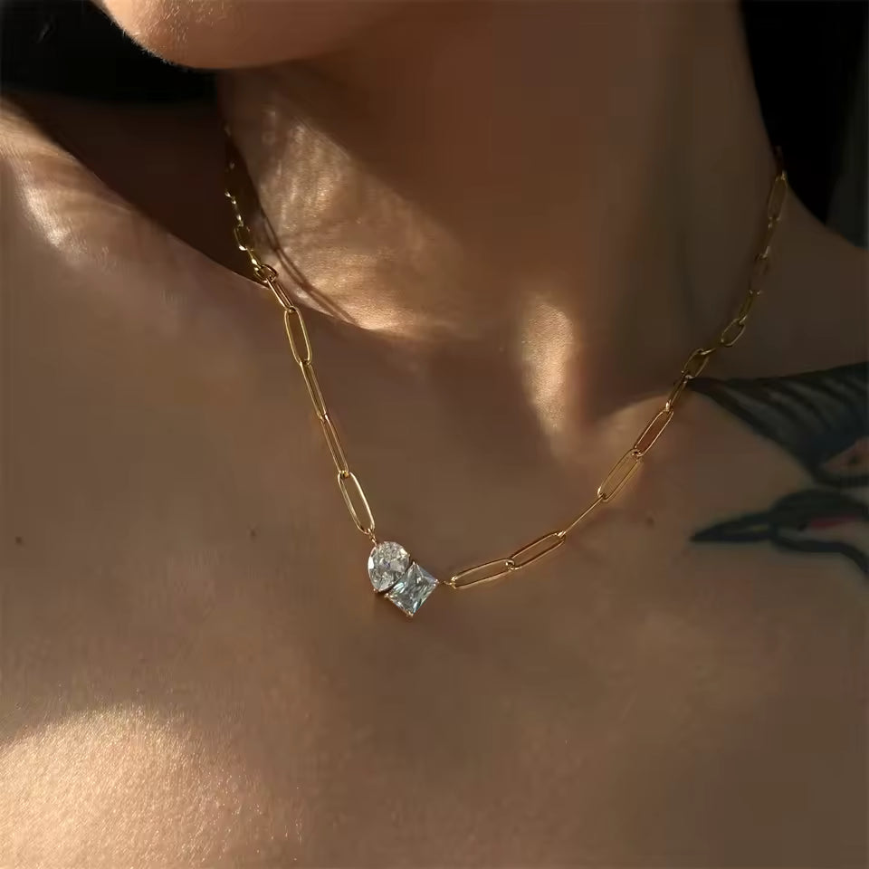 Paperclip gold chain with two large cubic zirconia's worn on woman with tattoo