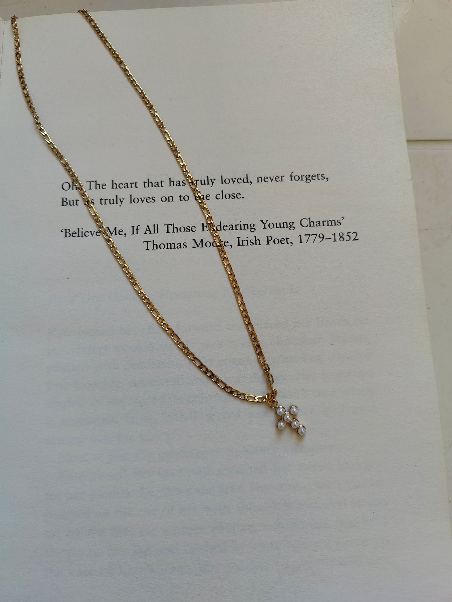 Gold necklace with a small pendant on a piece of paper with text