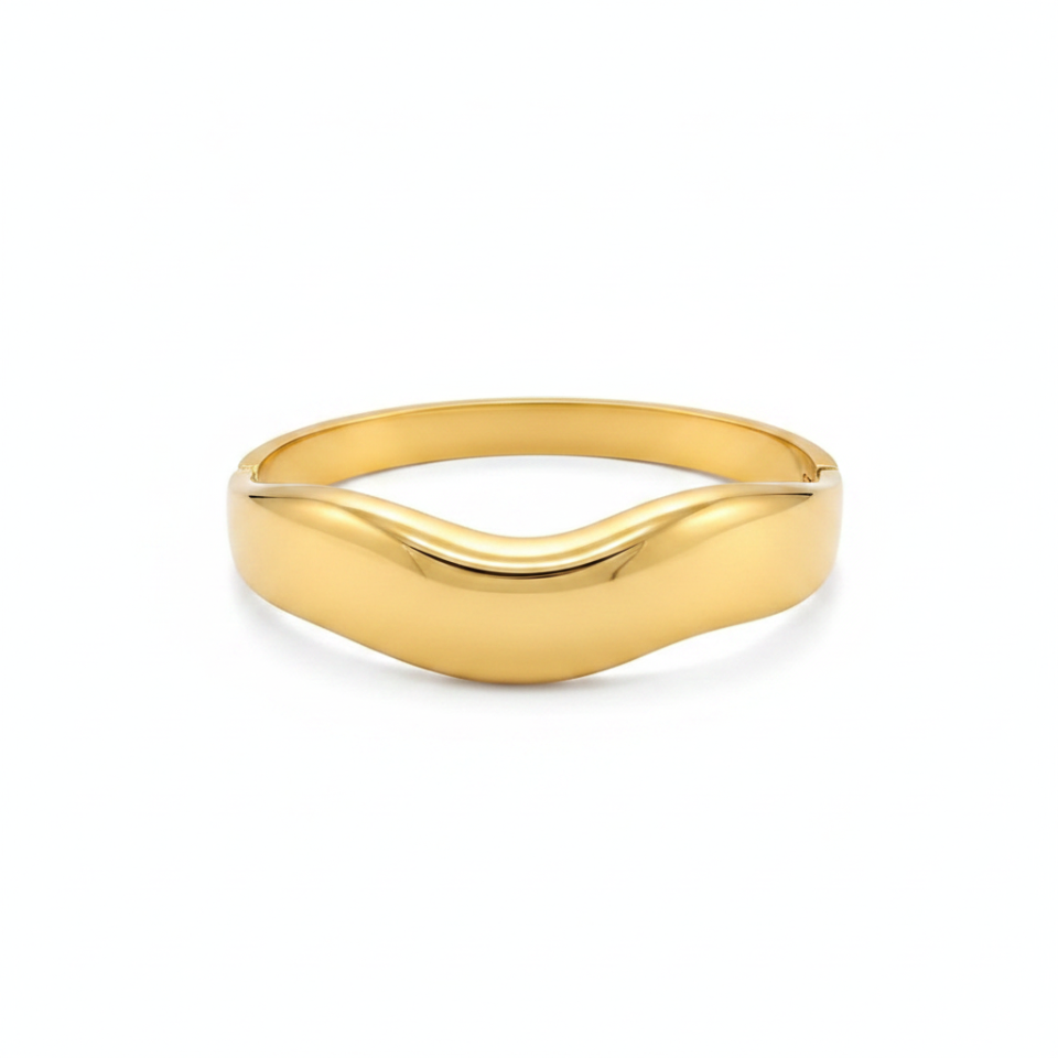 Gold cuff bracelet with wave design on white background