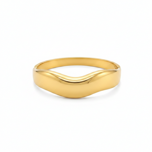 Gold cuff bracelet with wave design on white background