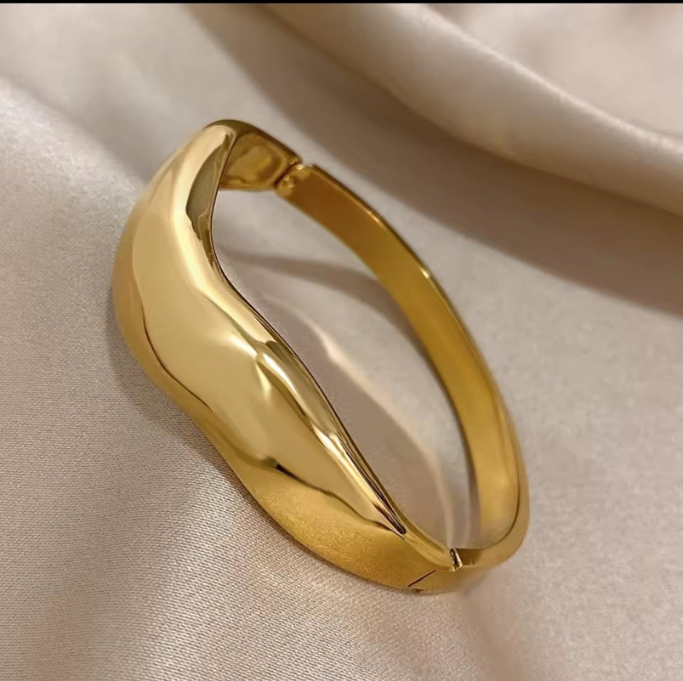 Gold bracelet on a beige fabric background