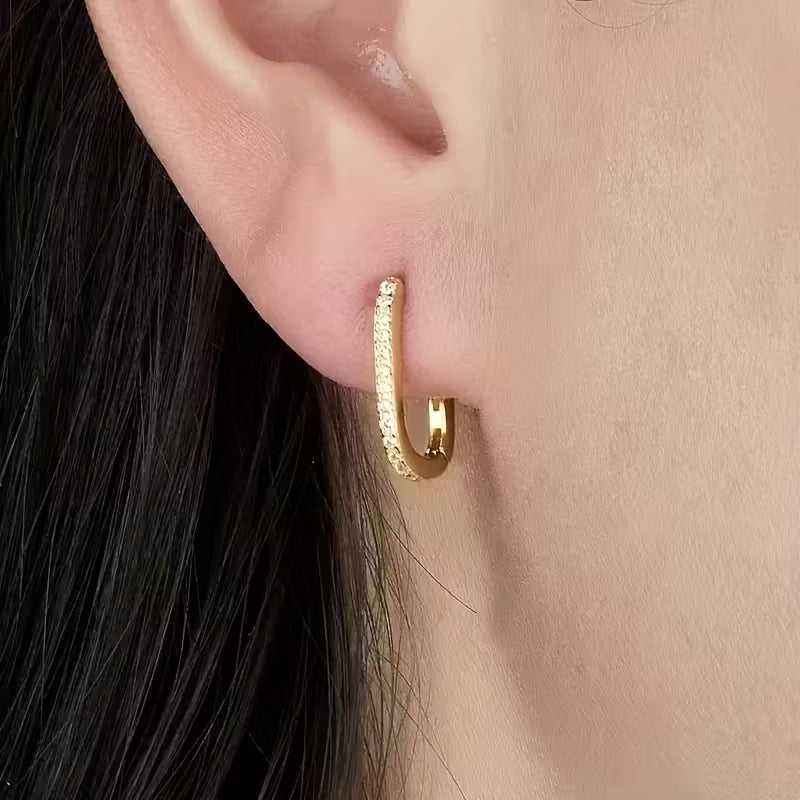 Gold hoop earring worn by a person with black hair.