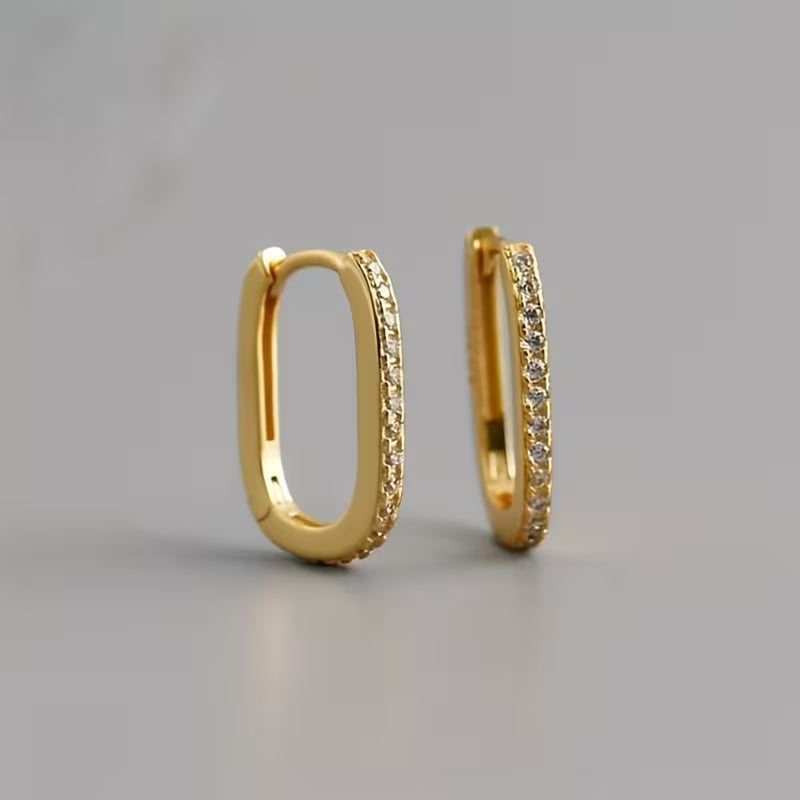 Gold hoop earrings with embedded stones on a gray background