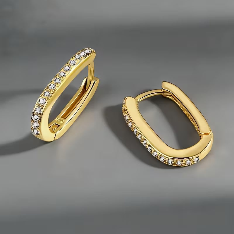 Gold hoop earrings with embedded stones on a gray background