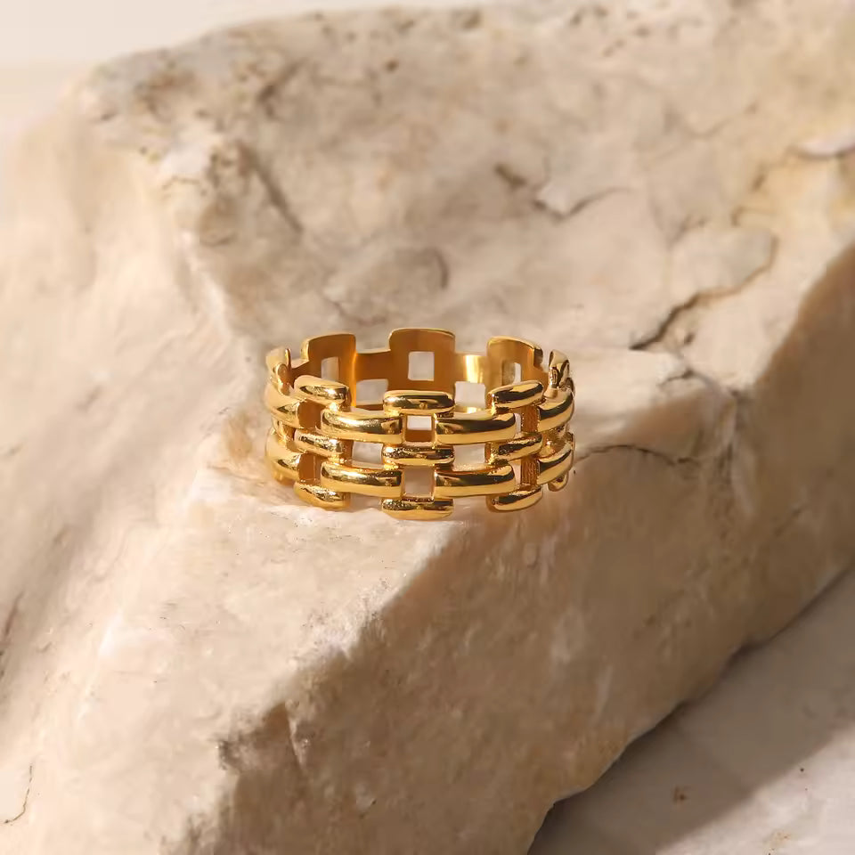Gold ring on a textured beige stone surface