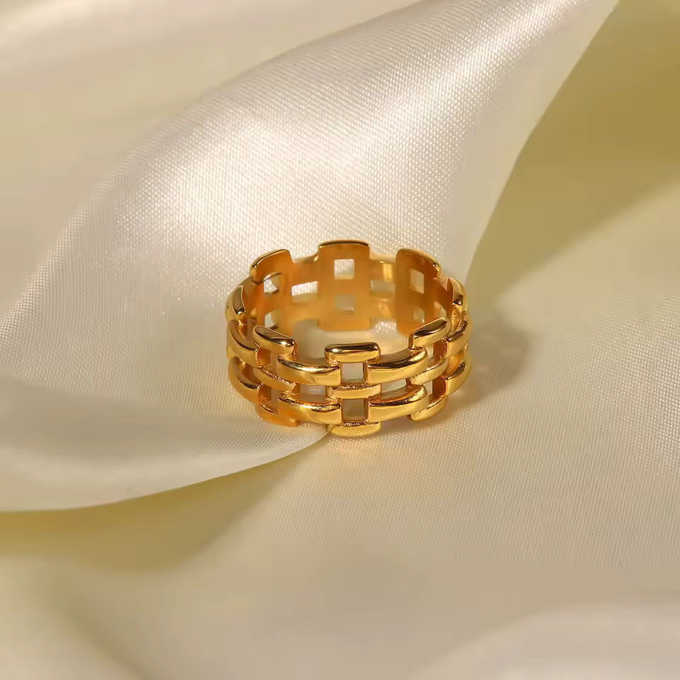 Gold ring with a geometric design on a beige fabric background