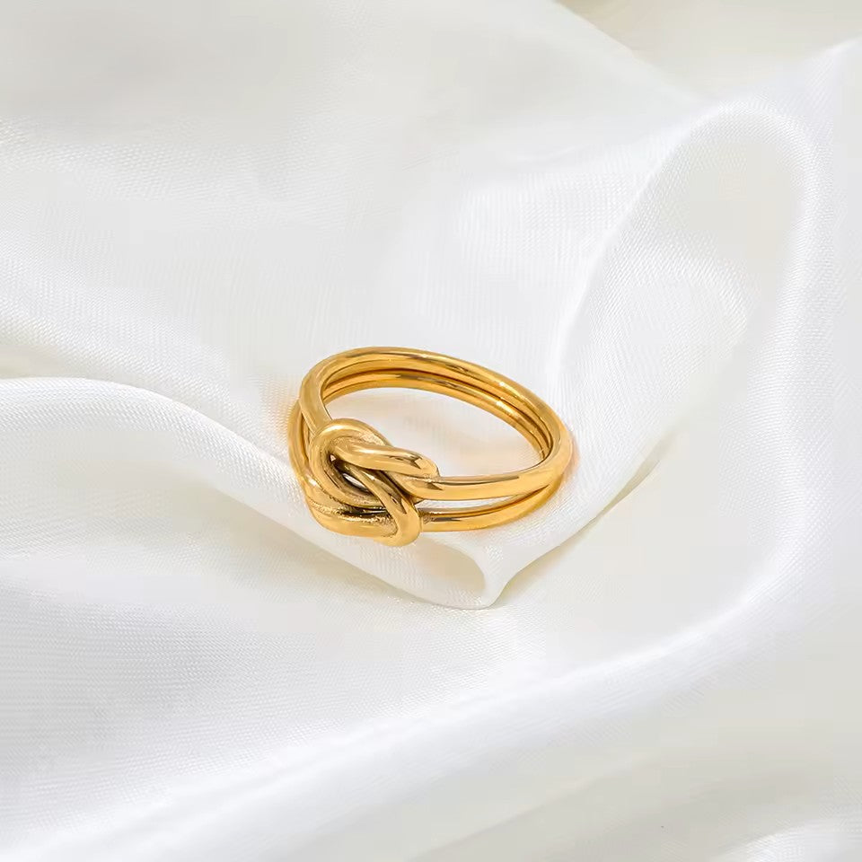 Gold knot ring on a white fabric background