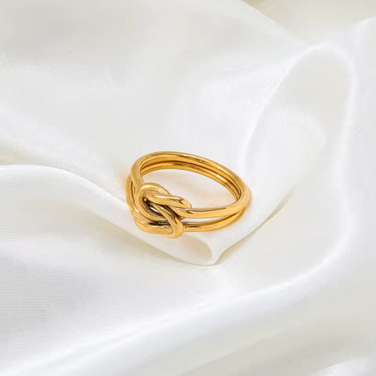Gold knot ring on a white fabric background