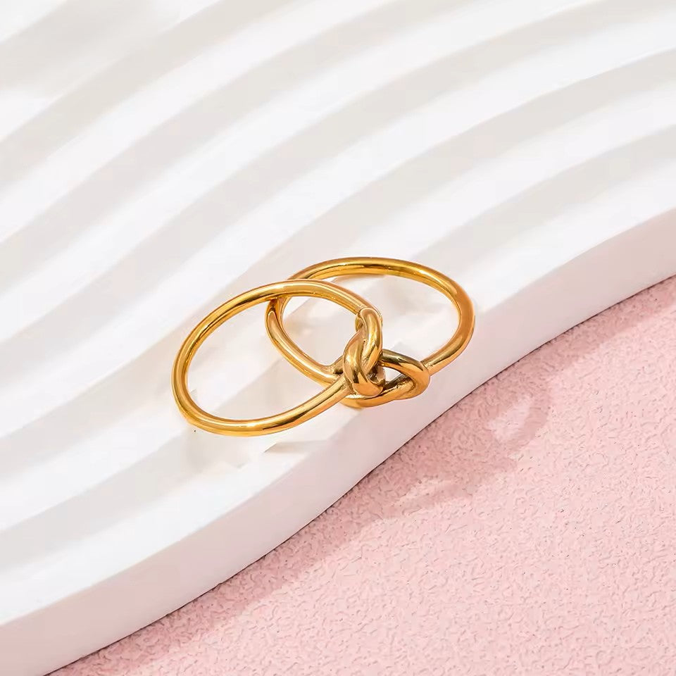 Two gold rings intertwined on a white and pink striped background