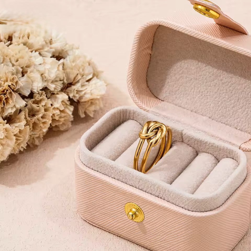 Gold ring in a pink jewelry box with flowers on a light background