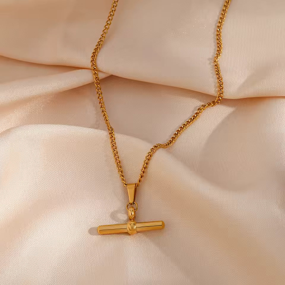 Gold necklace with a pendant on a beige fabric background