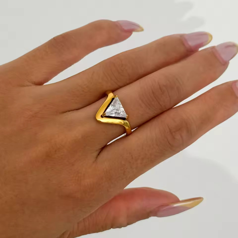 Gold ring with a triangular design on a hand against a white background