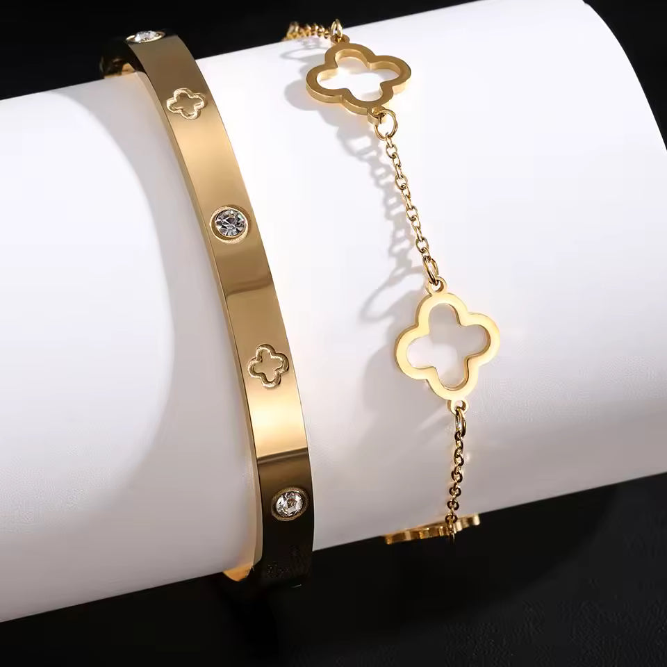 Gold bracelets with clover designs on a white surface
