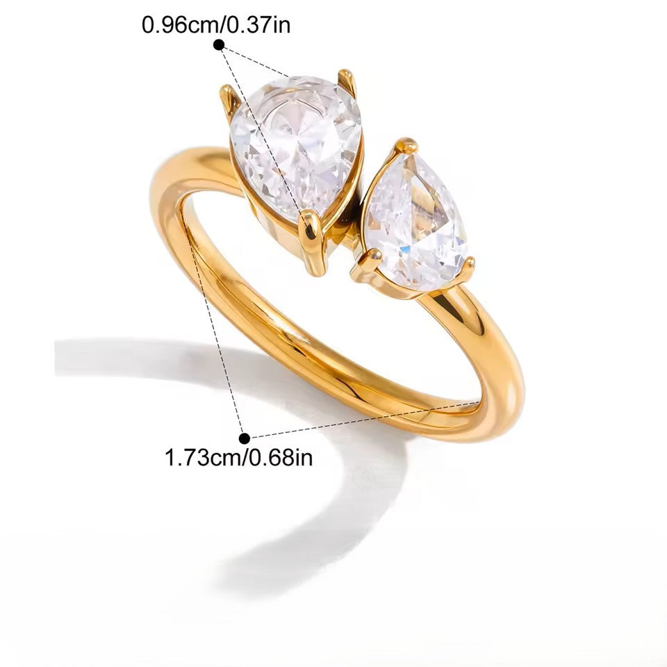 Gold ring with two pear-shaped clear gemstones on a white background