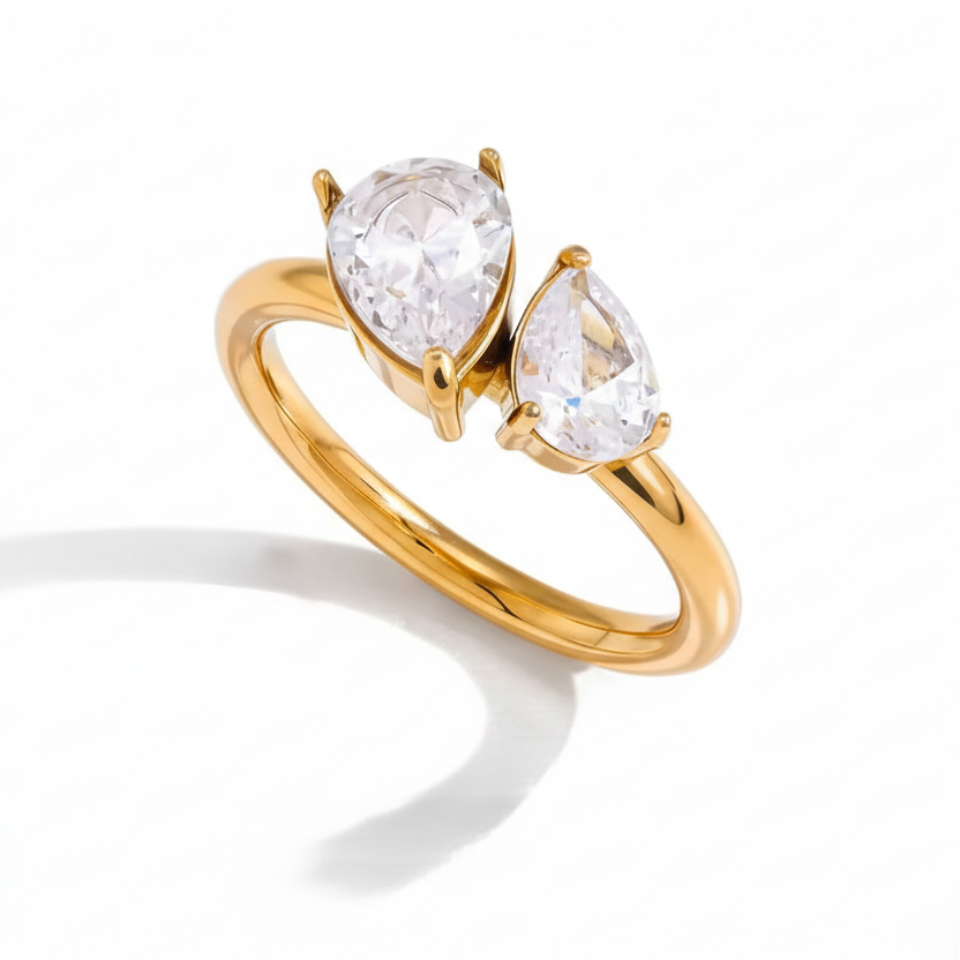 Gold ring with two pear-shaped clear gemstones on a white background