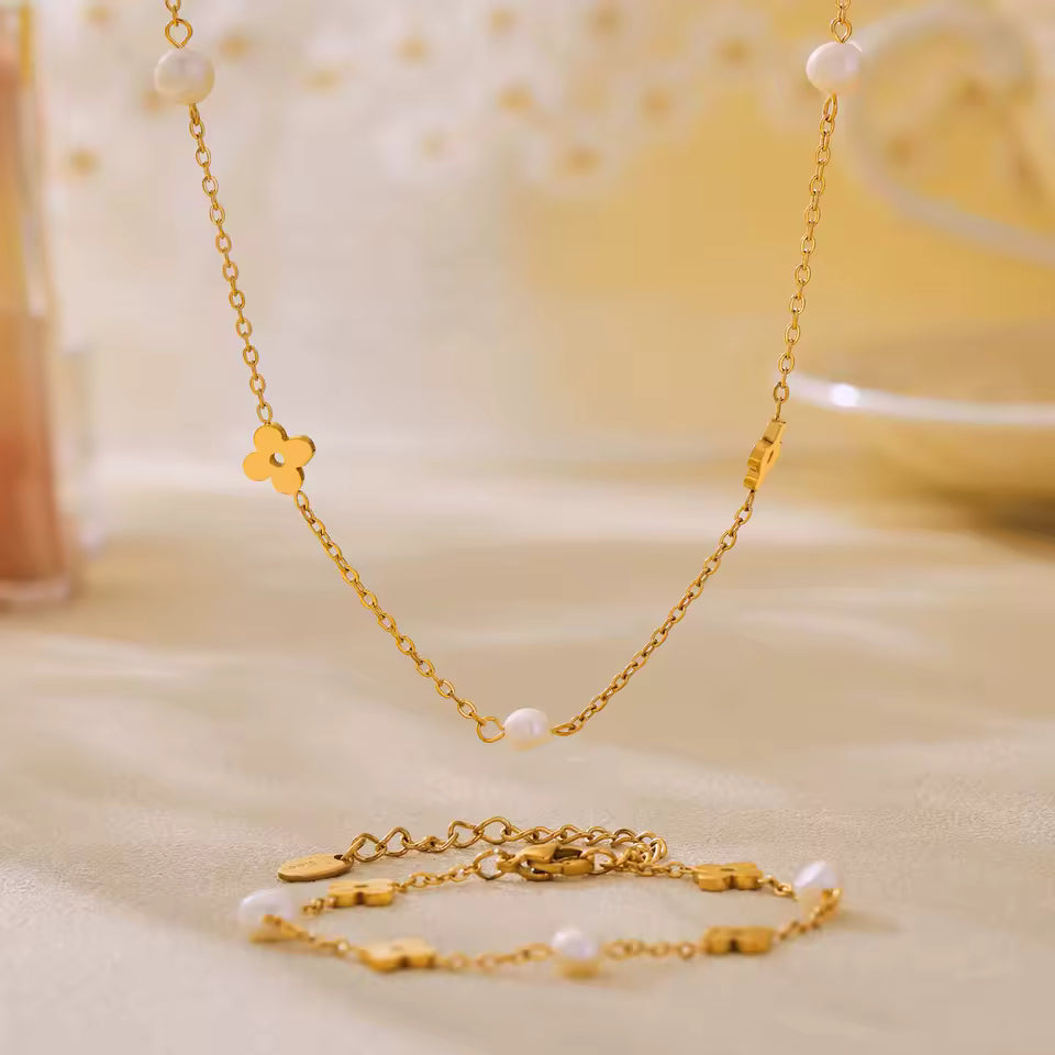 Gold necklace with floral design and freshwater pearls  on a soft beige background