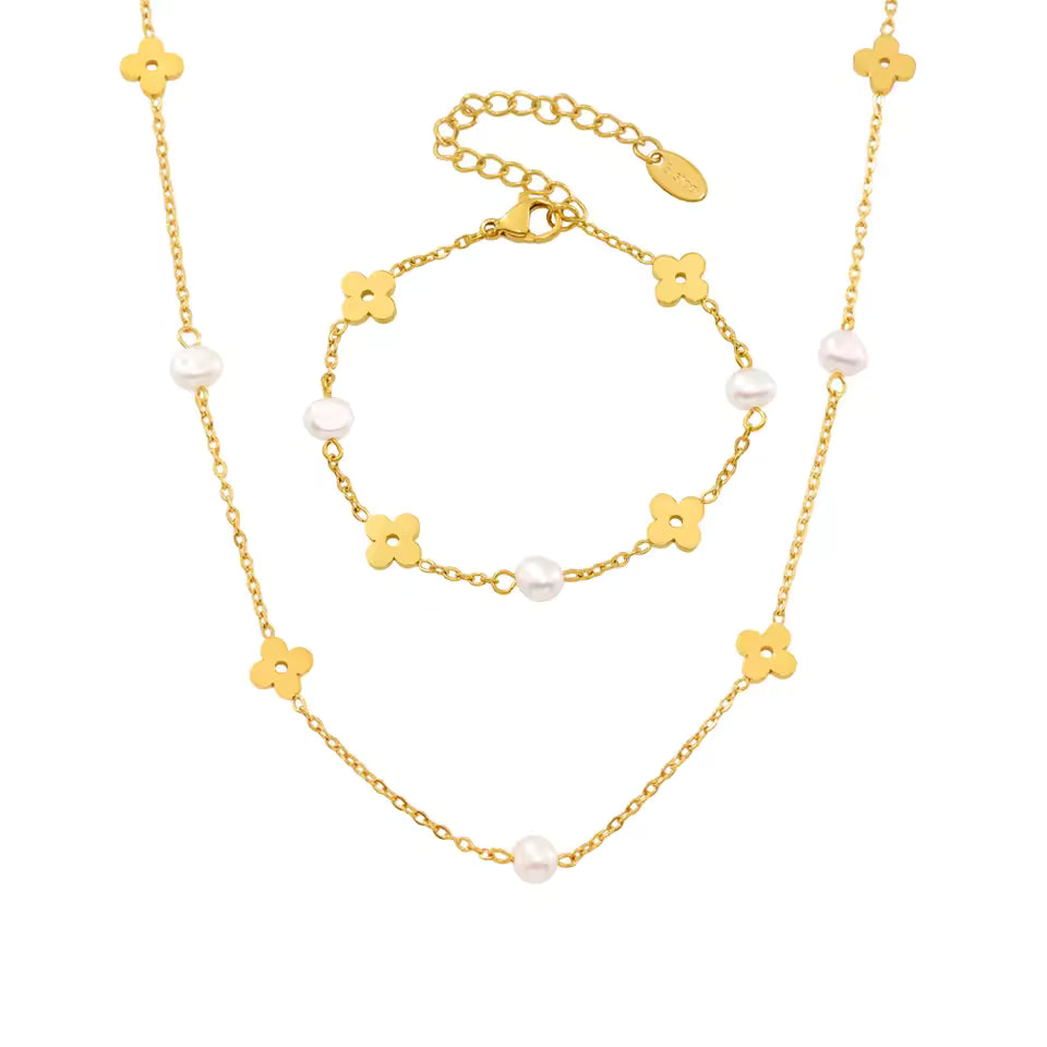 Gold necklace with floral and pearl details on a white background