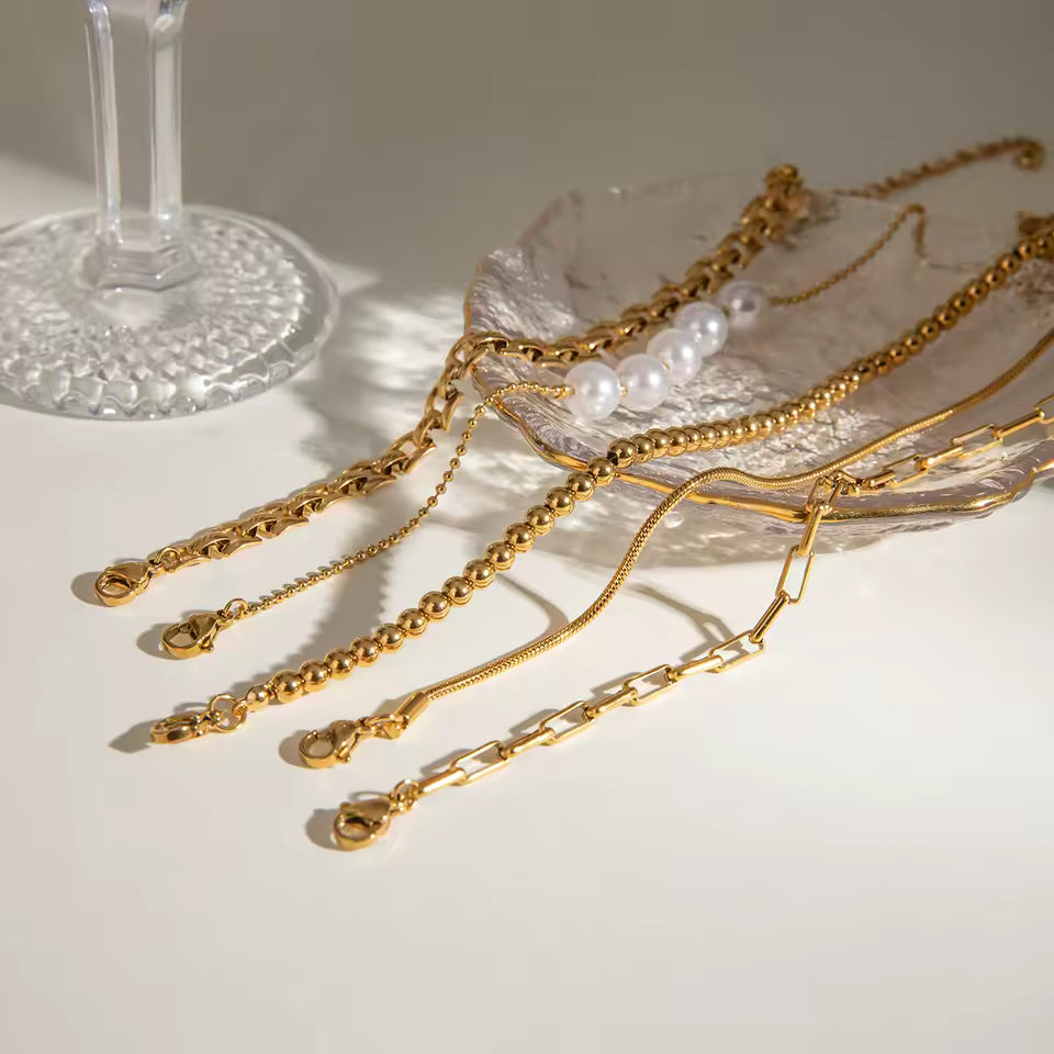 Gold bracelets with pearls on a white surface