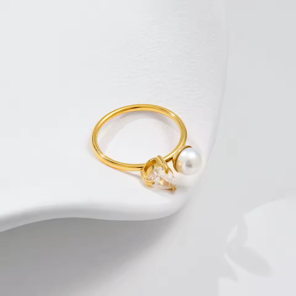 Ring with pearl and diamond setting laying on side on plain background