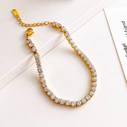 Gold bracelet with clear stones on a white background