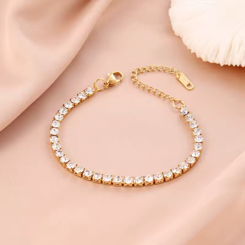 Gold bracelet with clear stones on a soft pink fabric background