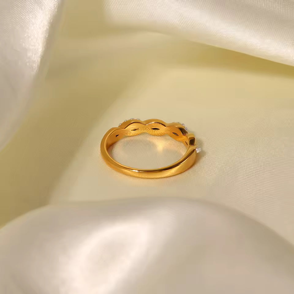 Gold ring with intricate design on a beige fabric background