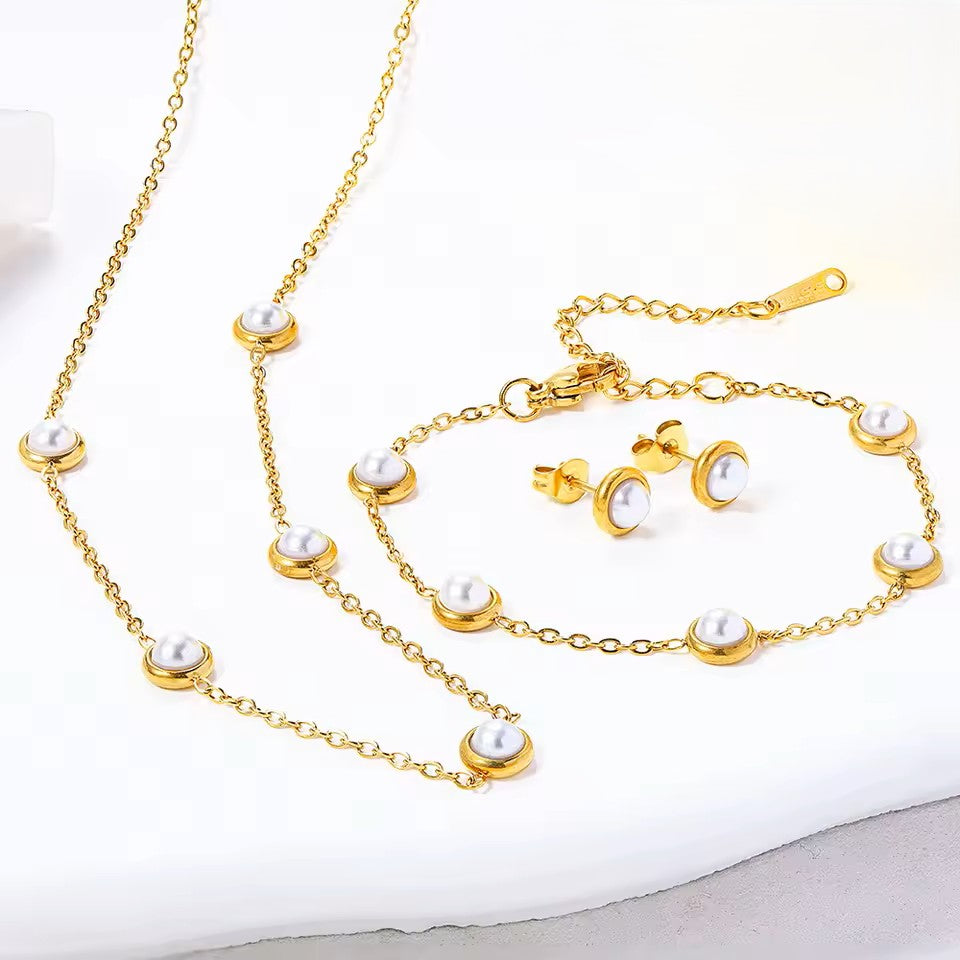 Gold necklace with pearl accents and matching earrings on a white background