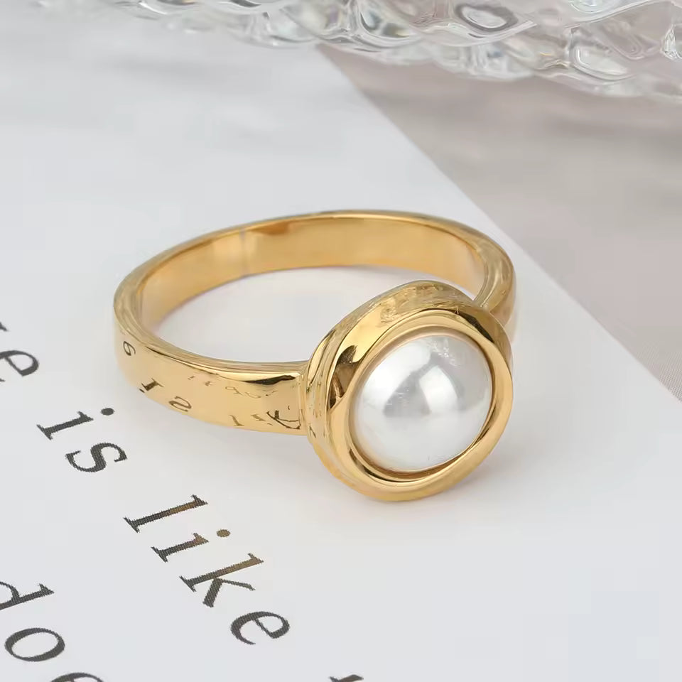 Gold ring with a pearl on a white surface