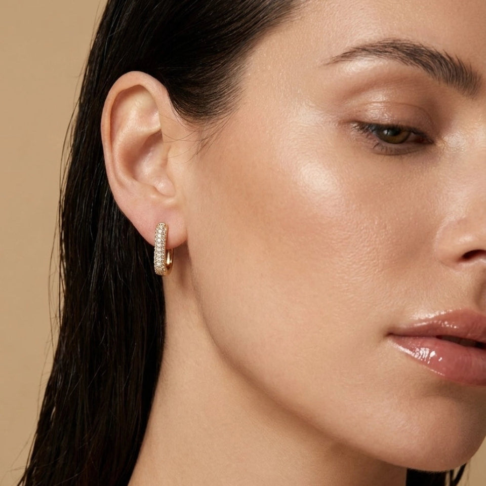 Close-up of a woman wearing a diamond earring against a beige background