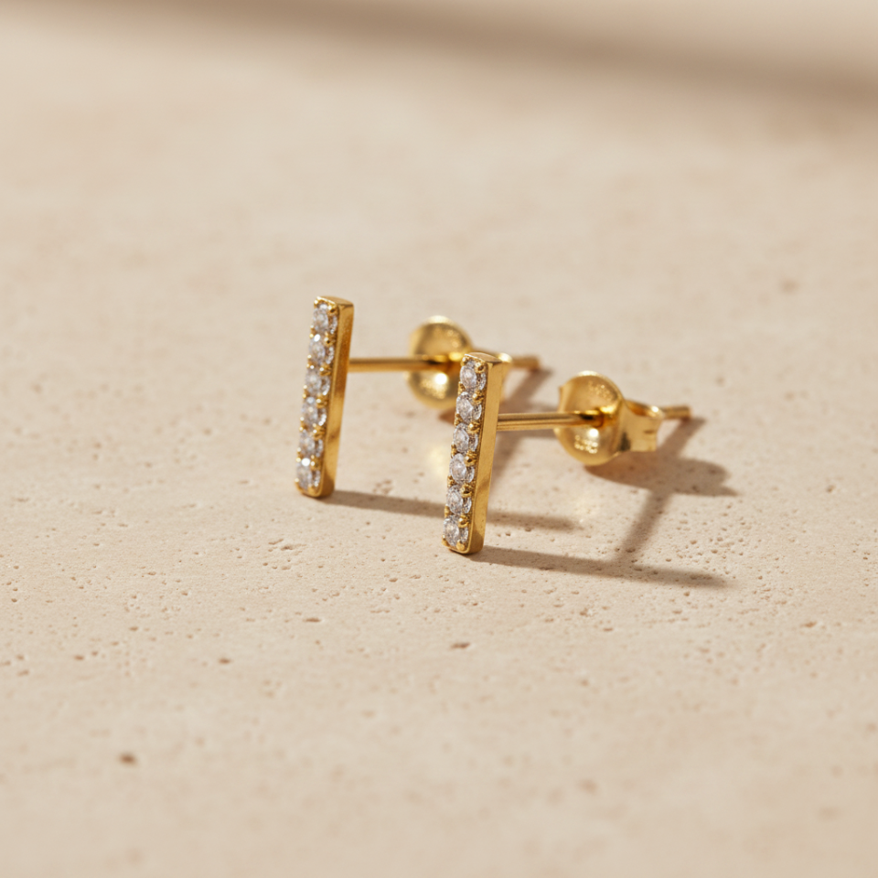 Remi gold-tone vertical bar stud earrings with clear pavé-style stones and butterfly backs in a close studio view