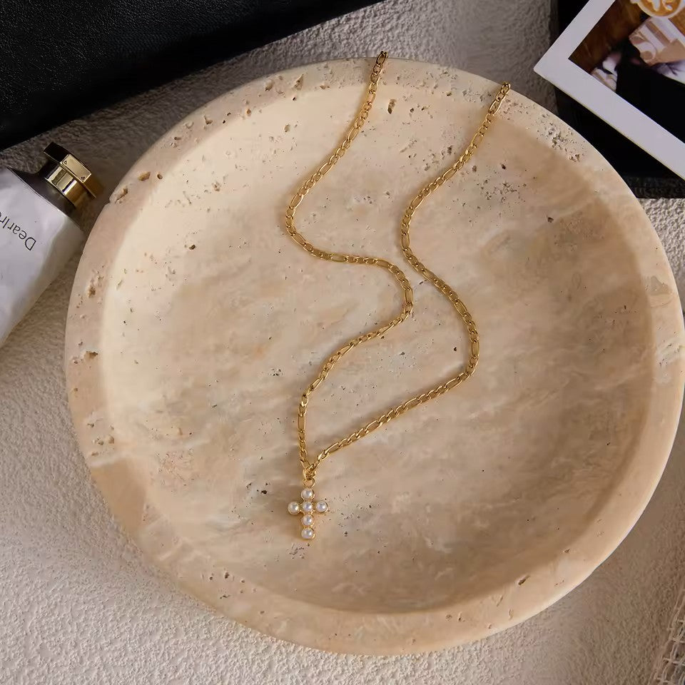 Gold necklace on a textured beige surface with a blurred background