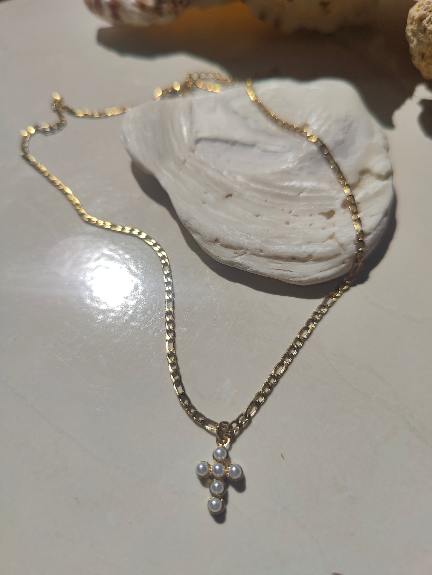 Gold necklace with a cross pendant on a light surface