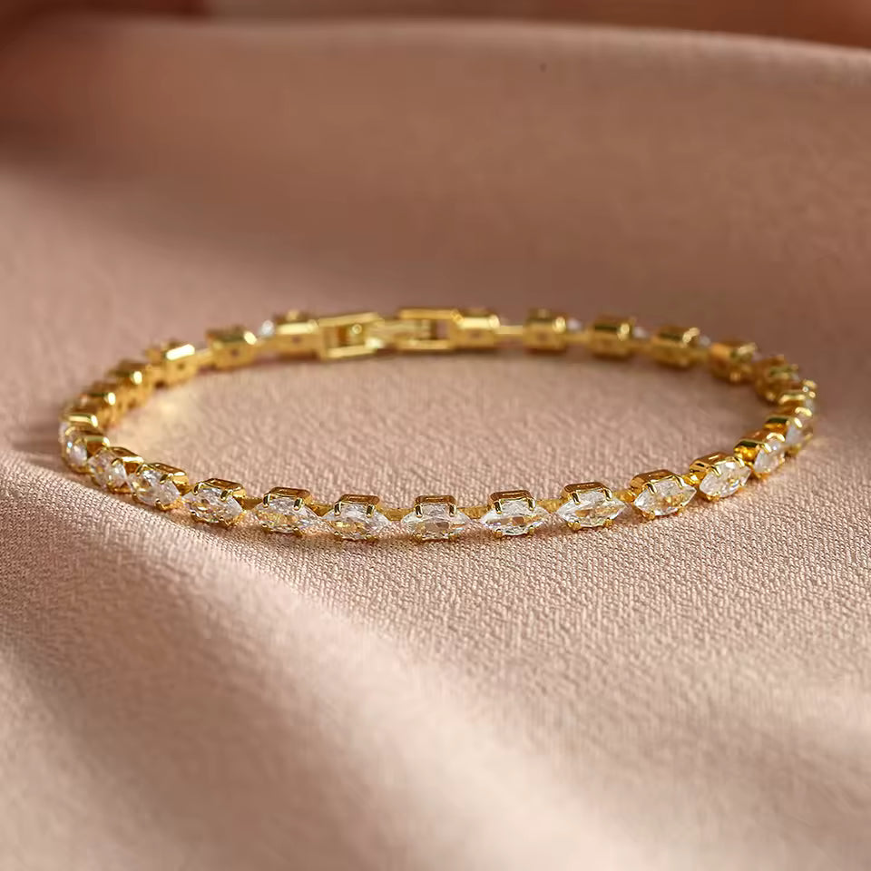 Gold bracelet with clear stones on a beige fabric background