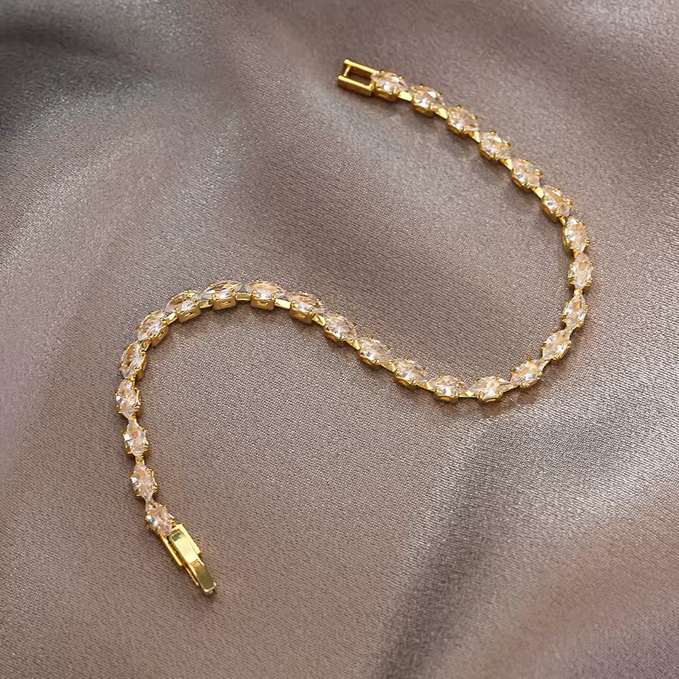 Gold bracelet with clear stones on a gray fabric background