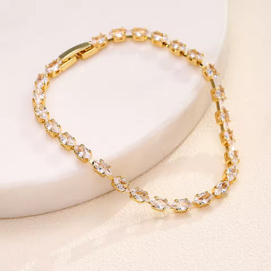 Gold bracelet with clear stones on a light background