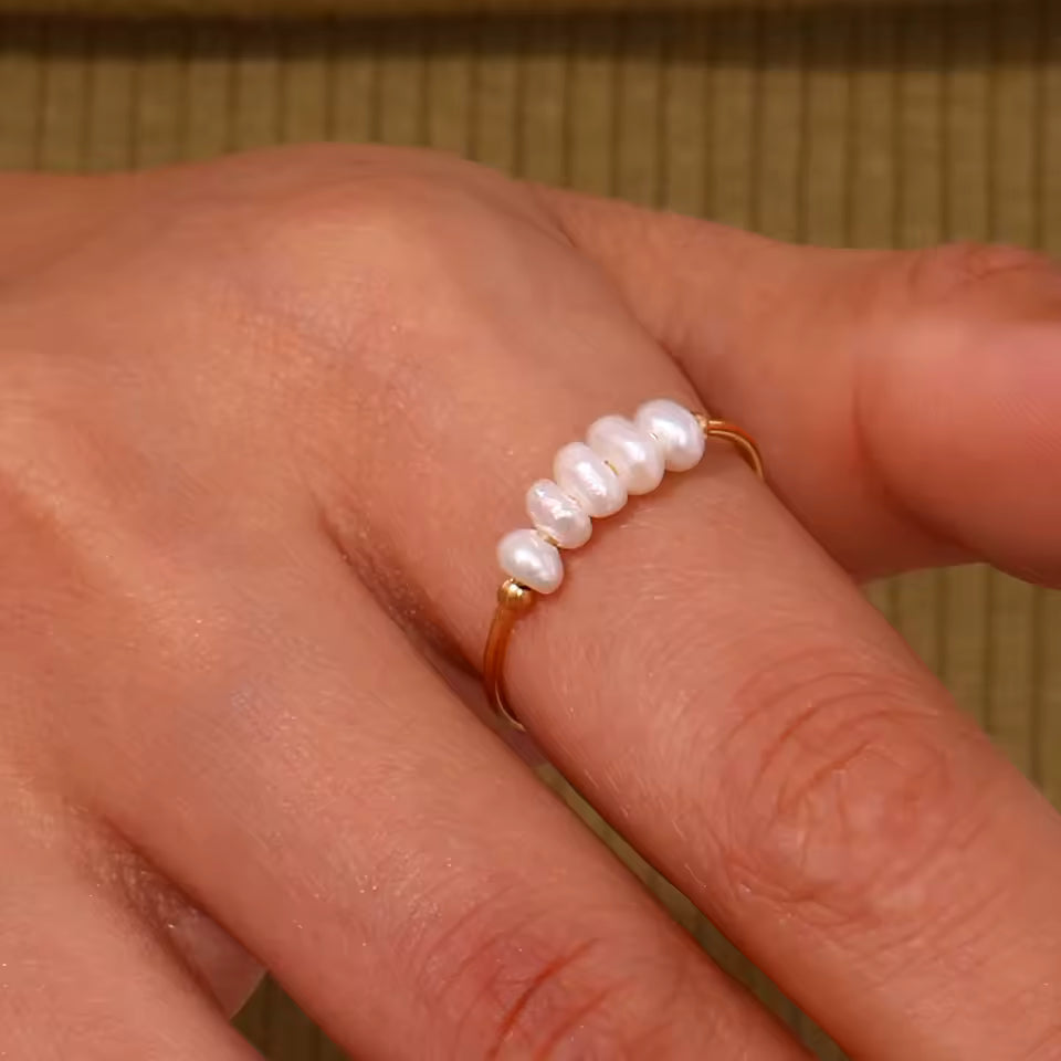 Pearl ring on a person's finger with a neutral background