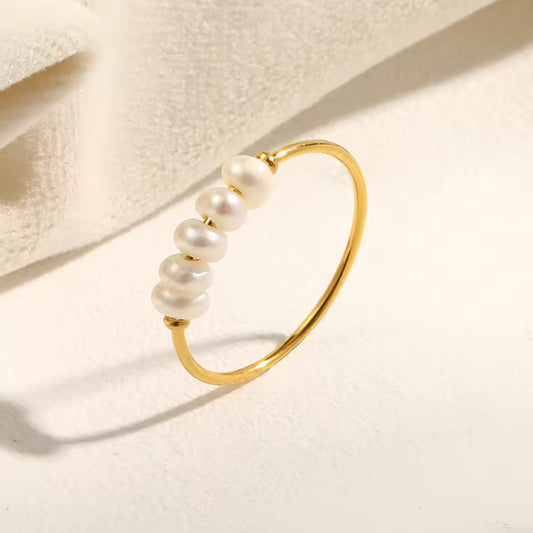 Gold ring with pearls on a light beige background